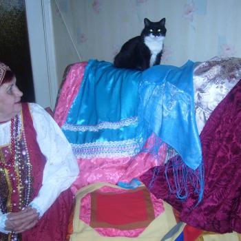Визит к информанту, Хилма Андреевна Исакова и её кошка на фоне карельских нарядов, г. Костомукша, Республика Карелия, февраль 2009 г.
